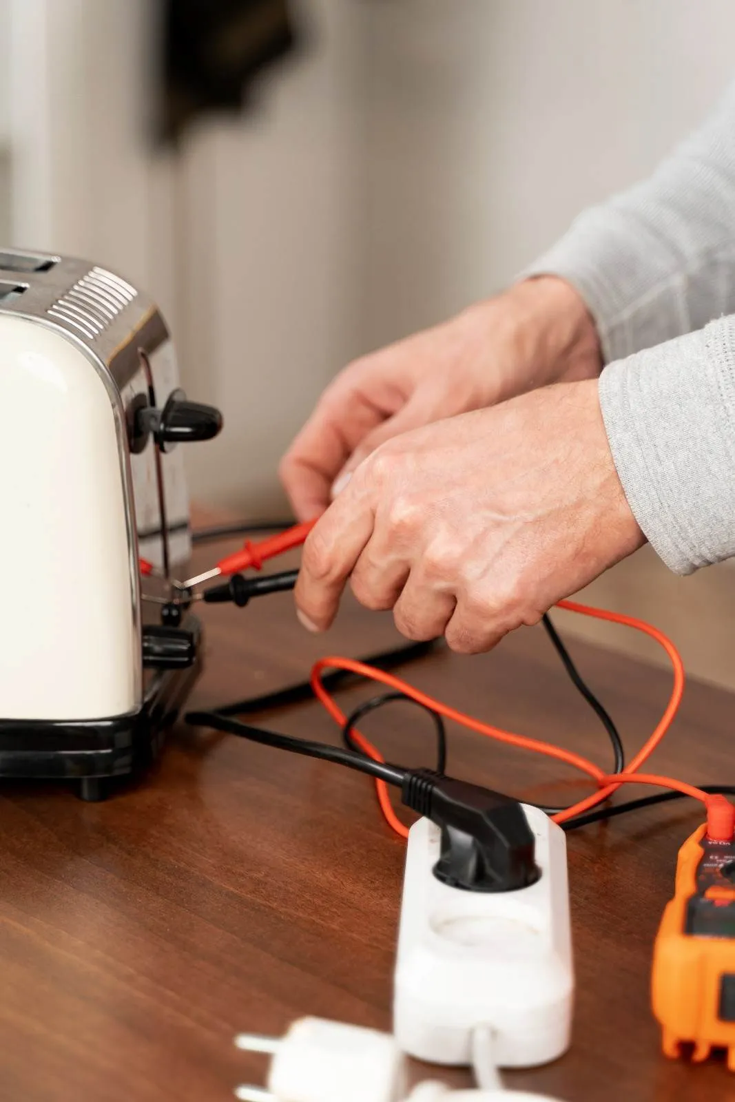 Technician testing the wiring of a kitchen appliance with a meter